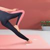 ピンクのヨガマットの上でストレッチする女性